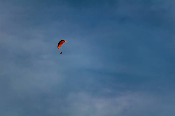 istock Paraglider on blue sky with orange parachute 1165300253