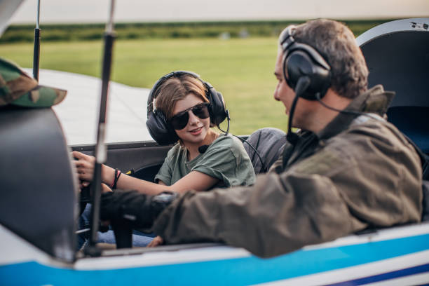 istock Young girl and pilot sitting in airplane cockpit 1165305302