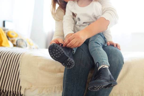 mother is tying a shoe of a child - shoe women adult baby imagens e fotografias de stock