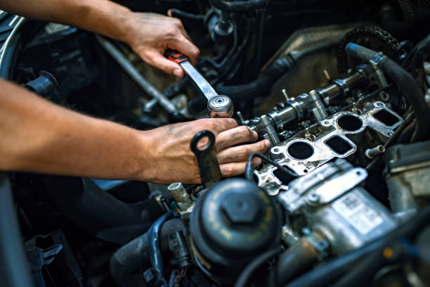 Mechanic using a ratchet wrench Car mechanic man at the garage fixing the engine. Hands of car mechanic with wrench in garage. Close up hands of unrecognizable mechanic doing car service and maintenance. Auto Service Business Concept. Pro Car Mechanic Taking Care of Vehicle. Checking Under the Car Hood. part of vehicle stock pictures, royalty-free photos & images