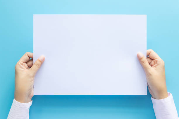 istock close up hands holding  empty white blank letter paper size A4 for flyer or invitation mock up isolated on a blue background. 1165318532