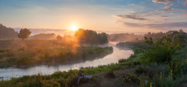 Panorama with river on foggy sunrise. Landscape with summer morning, clouds in sky