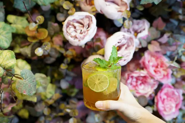 Photo of A glass of Mojito cocktail - Made with lime, mint, cane sugar and soda on blurred background.