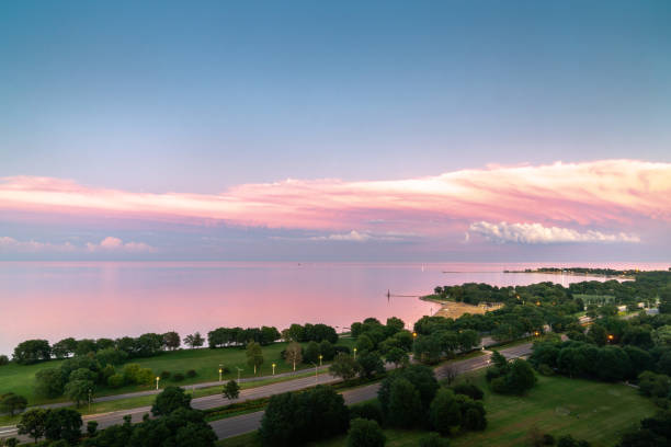 Gorgeous aerial sunset view of calm water of Lake Michigan with pink feathery clouds layered over white fluffy clouds and panoramic view of Montrose and Foster Beach along Lake Shore Drive in Chicago. stock photo