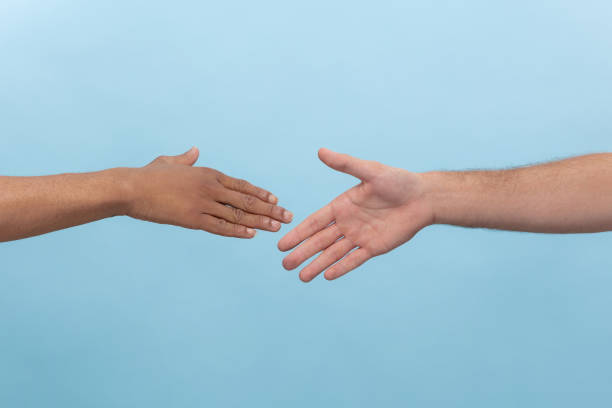 istock Close up shot of human holding hands isolated on blue studio background. 1165328155