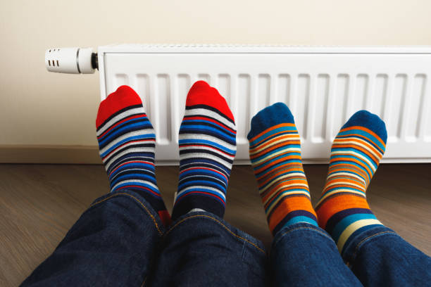 istock legs with colorful socks in front of heating radiator 1165329333