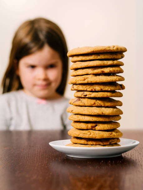 istock Young girl looking at a stack of cookies 1165334271