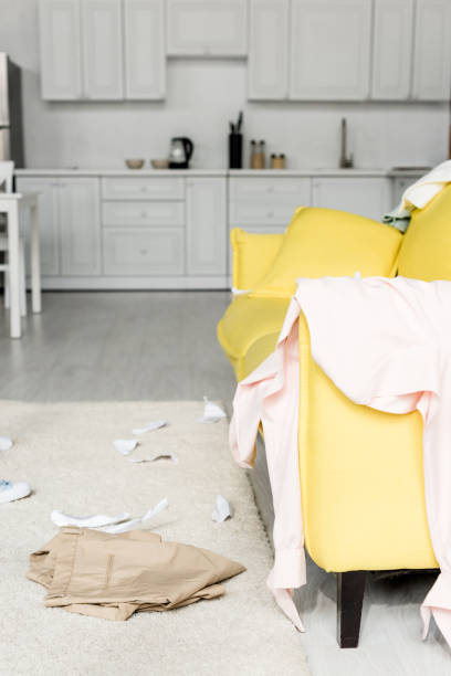 istock carpet and bright yellow sofa with cloths and papers 1165336321
