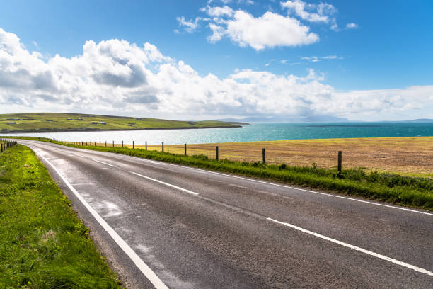 estrada vazia da costa ao lado de uma baía bonita e de um céu azul - landscape uk scotland scenics - fotografias e filmes do acervo