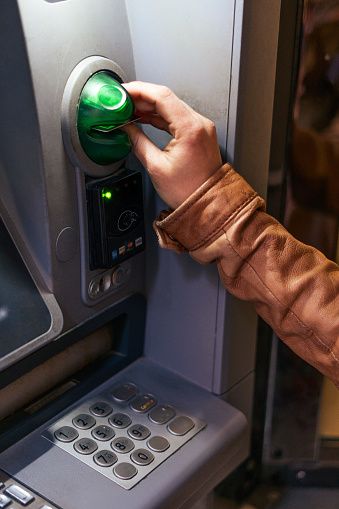 A young woman's hand withdrawing money from an ATM machine during her vacations in Venice, Italy.