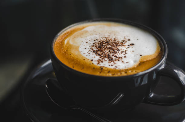 istock close up modern hot black coffee the cappuccino on dark background with coffee bubble foam pattern and texture in black cup looking and feel so delicious on glasses table in coffee shop. 1165340690