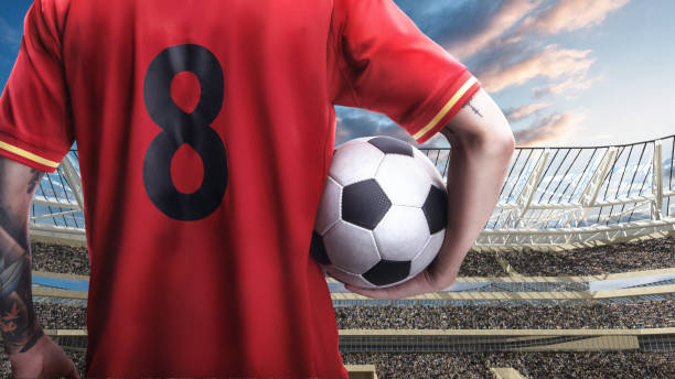 istock soccer player standing with the ball against the crowded stadium on background 1165341692