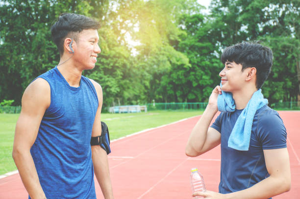 istock Two Man runners standing talking after running and training exercise in stadium, talking and smiling and drink water while resting 1165342203