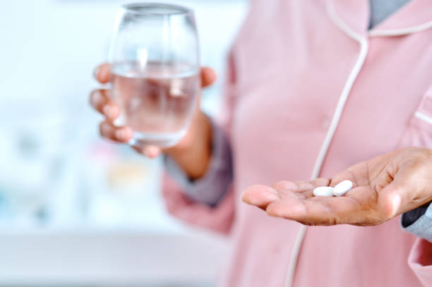 It's that time of day again Closeup of a n unrecognizable elderly woman holding pills in one hand and a glass of water in the other hand at home during the day Anti Aging supplements stock pictures, royalty-free photos & images