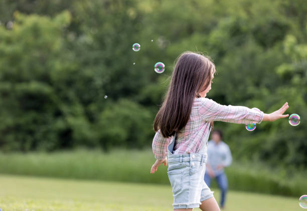 istock Little girl runs through bubbles in a park 1165344863
