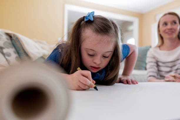 istock Special needs girl focuses intently on coloring 1165345292