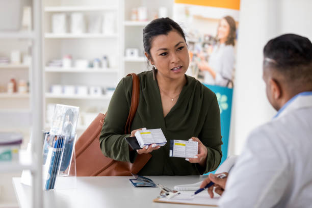 Pharmacist asks pharmacist question about medication Serious pharmacy customer asks a male pharmacist for his opinion on two different cold medications. generic description stock pictures, royalty-free photos & images