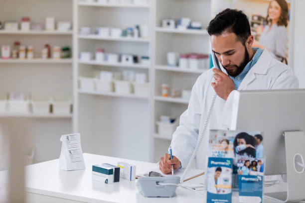 istock Male pharmacist talks on phone with customer 1165345999