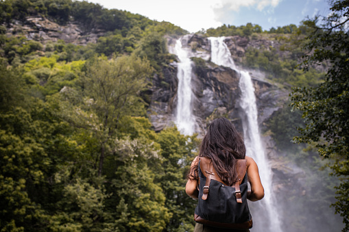 Latin woman visiting beautiful waterfall in Italy.