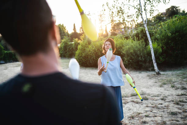 Two young adult jugglers training together at the park