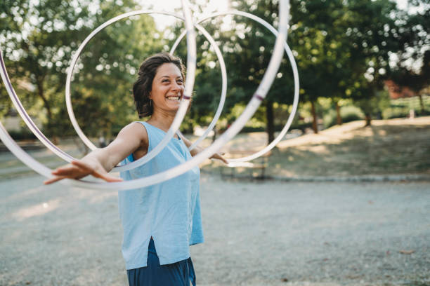 Young adult woman juggling with hula hoop at the public park Young adult woman juggling with hula hoop at the public park juggling stock pictures, royalty-free photos & images