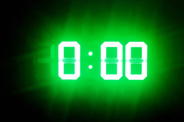 istock Green glowing digits in the dark show 0:00. Midnight time. 1165346815
