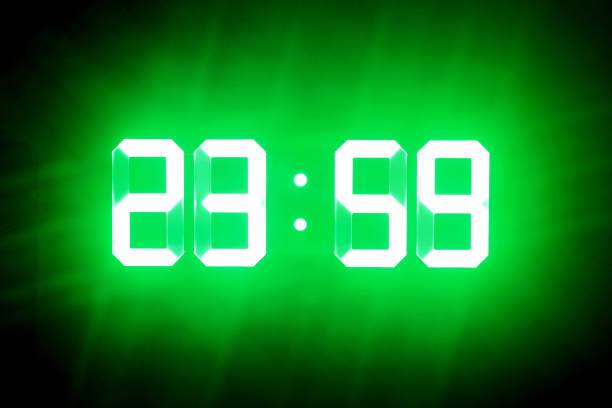 le cifre incandescenti verdi al buio mostrano 23:59. l'ora è di un minuto a mezzanotte. - numero 59 foto e immagini stock