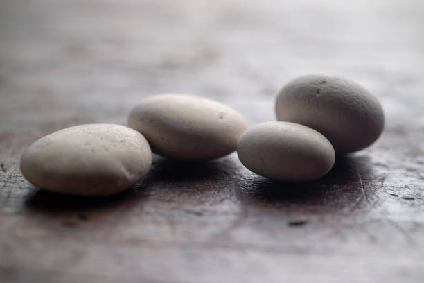 istock four little white fluvial stones on wooden surface 1165348201