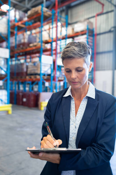 istock Female manager writing on clipboard in warehouse 1165352814