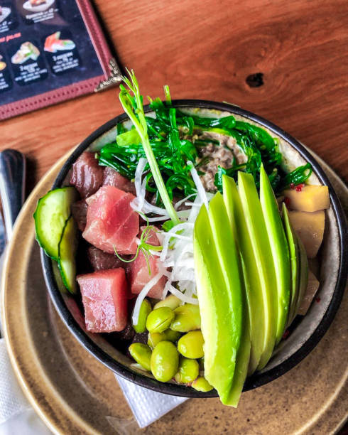 Vegetable salad with tuna fillet in a black bowl .Top view with copy space.