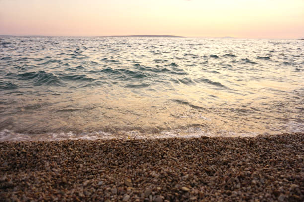 istock Beautiful seashore and sea tide on a pebble beach at sunset 1165354121