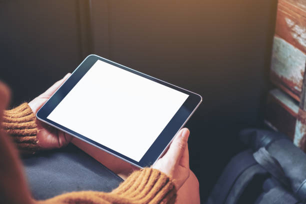 istock a woman sitting and holding black tablet pc with blank white desktop screen 1165356880