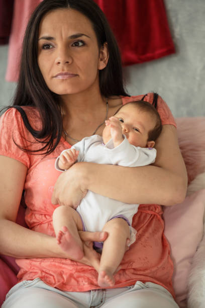 istock Serious mother holding baby in her arms 1165357259