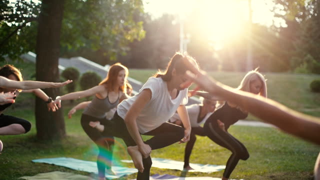 Group of young woman in sportswear are standing in yoga position on one leg