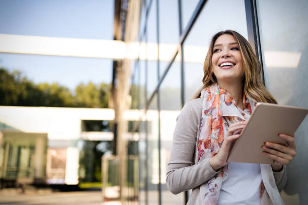 istock Beautiful young woman using tablet in the city 1165363618