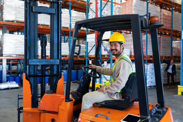 istock Male worker sitting in forklift and looking at camera in warehouse 1165363891