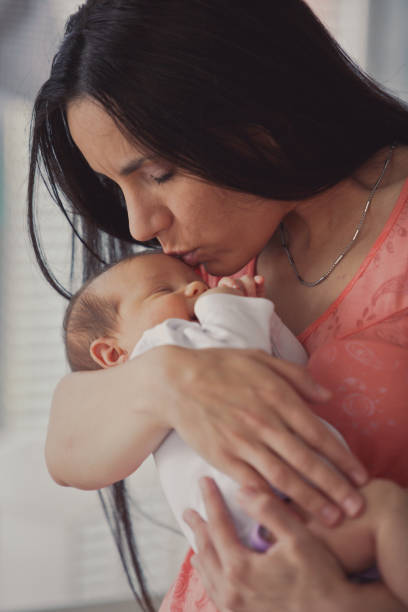 istock Mother kissing her baby's forehead 1165363938