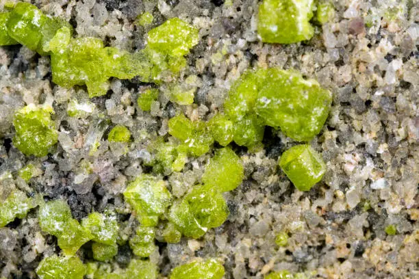 Closeup of a peridot or olivin mineral stone pattern background, details and macro of mineralogy