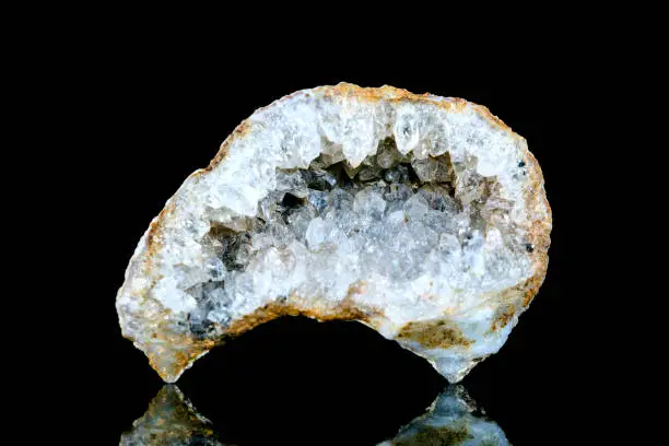 Raw quartz druse or geode mineral stone in front of black background, mineralogy and esotericism