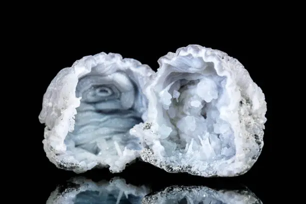 Two raw quartz druse or geode mineral stone in front of black background, mineralogy and esotericism