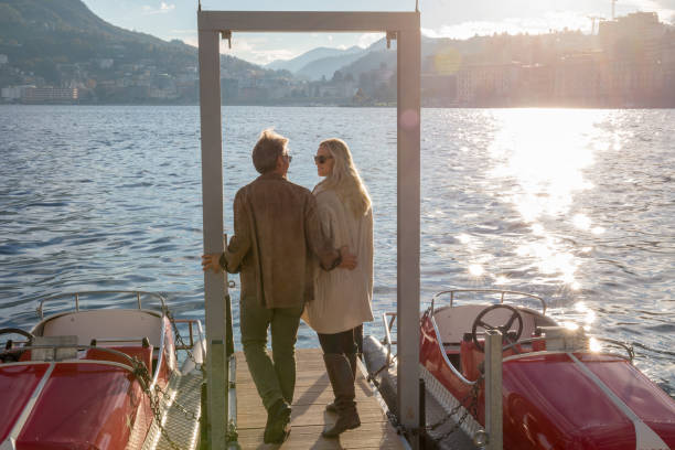 istock Couple walk along dock on a sunny lake in the mountains 1165365230