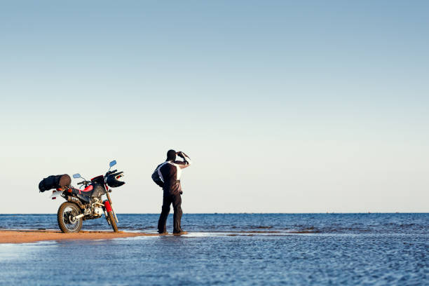 istock Biker with a motorcycle on the beach. 1165365966