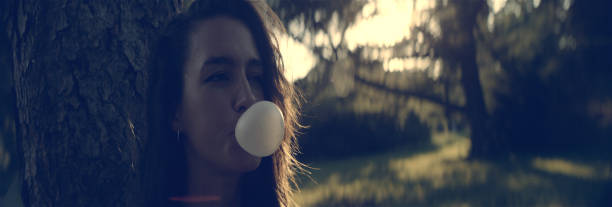 urocza dziewczyna z gumą bąbelkową. letni dzień w parku - chewing gum women bubble blowing zdjęcia i obrazy z banku zdjęć