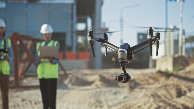 Two Specialists Use Drone on Construction Site. Architectural Engineer and Safety Engineering Inspector Fly Drone on Commercial Building Construction Site Controlling Design and Quality. Focus on Drone