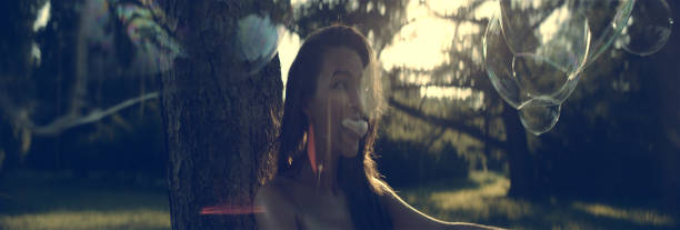 urocza dziewczyna z gumą bąbelkową. letni dzień w parku - chewing gum women bubble blowing zdjęcia i obrazy z banku zdjęć