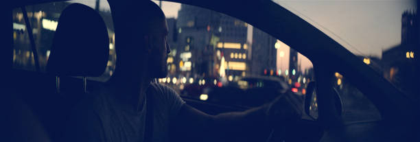 istock Happy man driving through city at sunset 1165368097