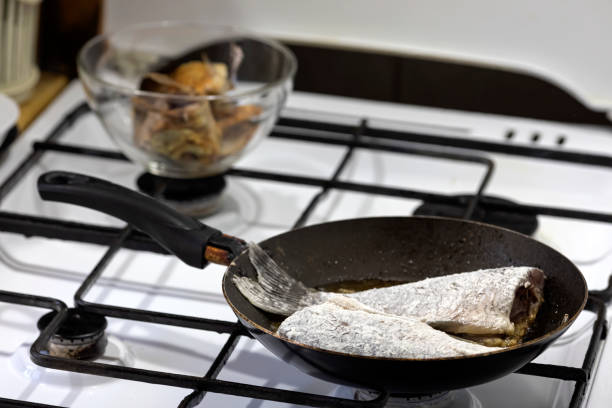 Pieces of river fish are fried in a pan on the stove. Cooking at home.
