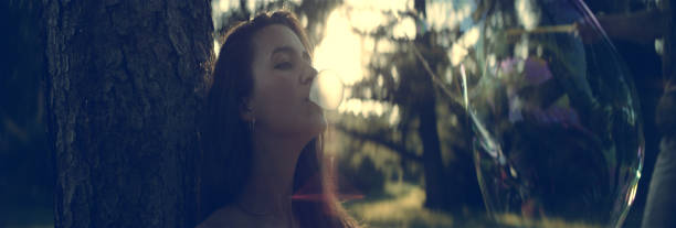 bonita chica con un chicle. día de verano en el parque - chewing gum women bubble blowing fotografías e imágenes de stock