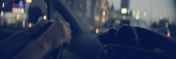 istock Man driving through city at sunset. Hands on wheel 1165368365
