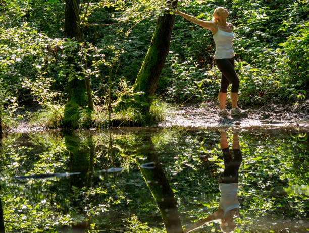istock Mature woman relaxes in forest by pond 1165368421